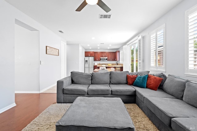 living room with ceiling fan, baseboards, visible vents, and wood finished floors