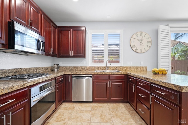 kitchen featuring a sink, stainless steel appliances, reddish brown cabinets, and recessed lighting