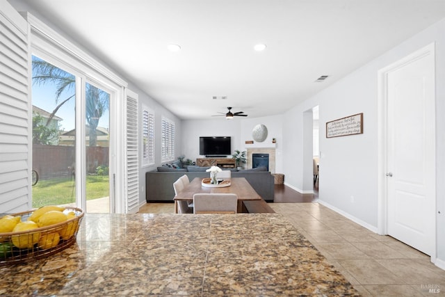 living room with ceiling fan, tile patterned floors, plenty of natural light, and a tile fireplace