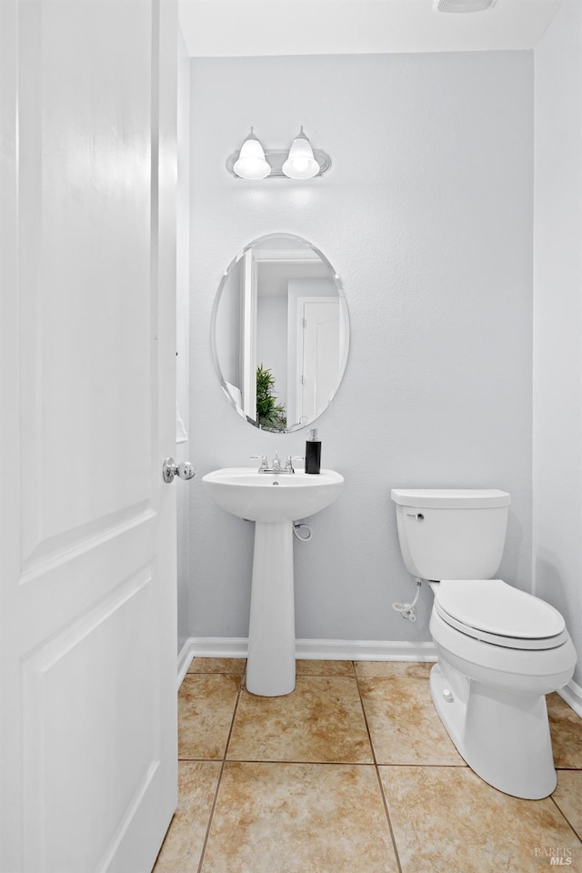 bathroom with toilet, baseboards, and tile patterned flooring