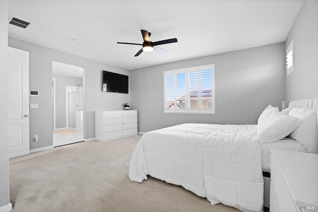 carpeted bedroom featuring a ceiling fan, multiple windows, ensuite bathroom, and visible vents