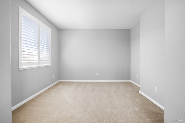 spare room featuring carpet flooring and baseboards