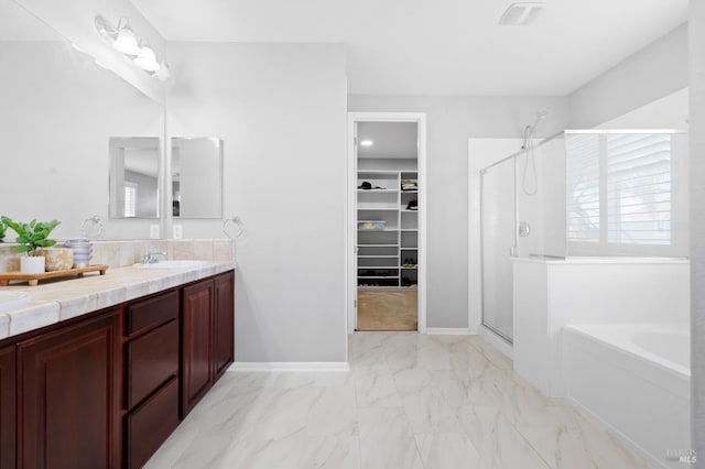 bathroom featuring double vanity, a garden tub, a shower stall, marble finish floor, and a spacious closet