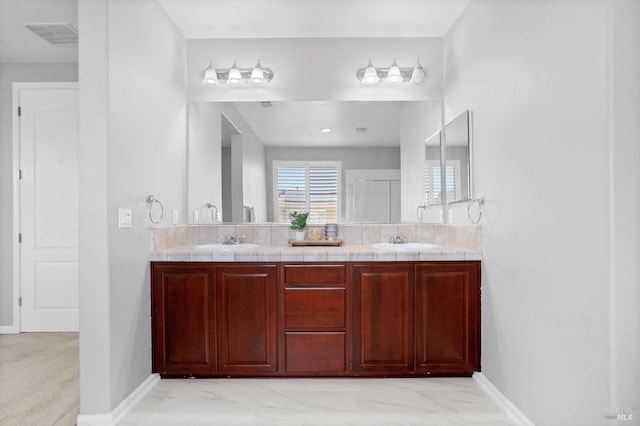 bathroom featuring double vanity, baseboards, and a sink