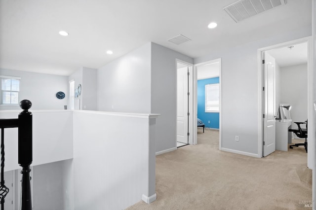 corridor with baseboards, light colored carpet, visible vents, and plenty of natural light