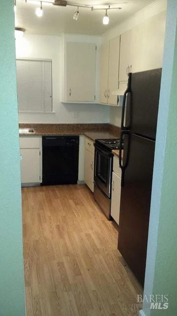 kitchen with white cabinets, dark countertops, light wood-style floors, and black appliances