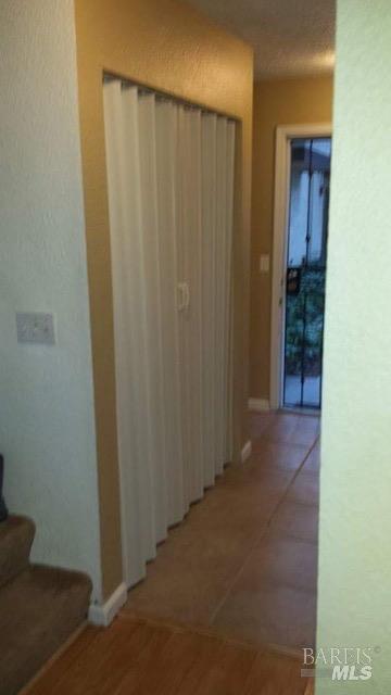 corridor with light tile patterned floors and baseboards