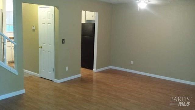 spare room with wood finished floors, baseboards, and ceiling fan