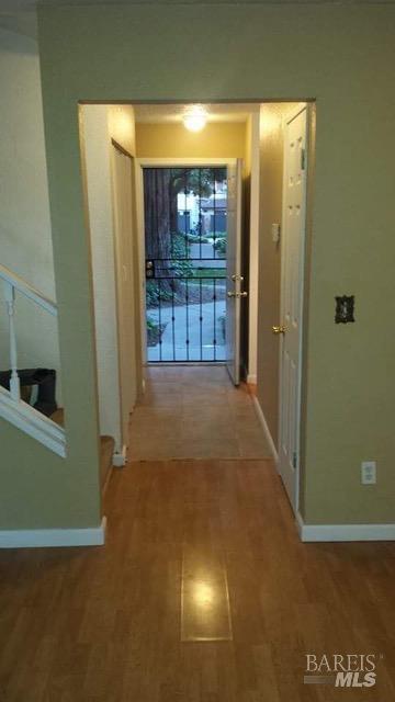 corridor featuring wood finished floors and baseboards