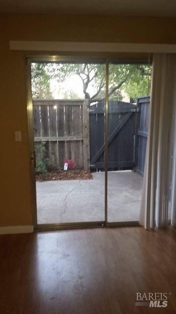 doorway featuring wood finished floors and baseboards