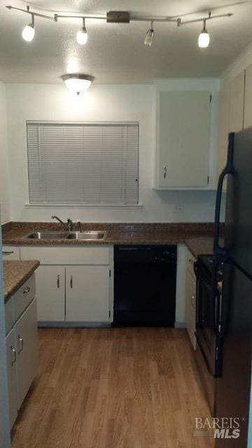 kitchen with a sink, white cabinets, black appliances, and wood finished floors
