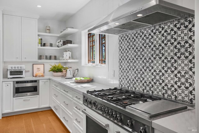 1071 Bale Ln, Calistoga, CA 94515 - kitchen with light countertops, a toaster, white cabinets, wall chimney range hood, and appliances with stainless steel finishes