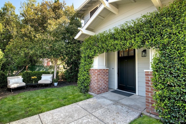 property entrance with a lawn, brick siding, and covered porch