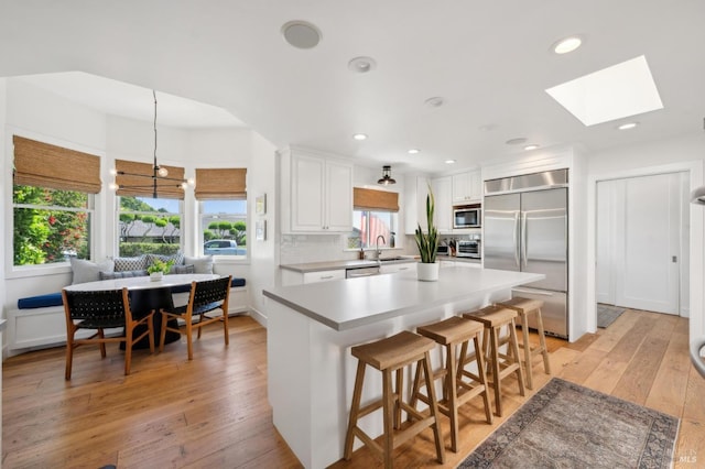 271 Via La Paz Rd, Greenbrae, CA 94904 - kitchen featuring a skylight, built in appliances, a breakfast bar area, light wood-style flooring, and white cabinets
