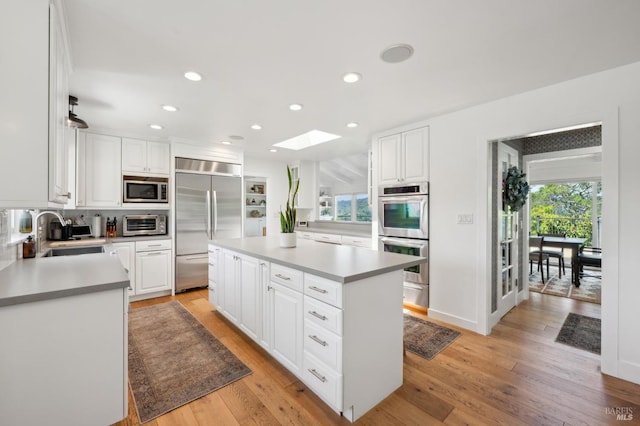 271 Via La Paz Rd, Greenbrae, CA 94904 - kitchen featuring built in appliances, light wood-style flooring, a center island, a sink, and a skylight
