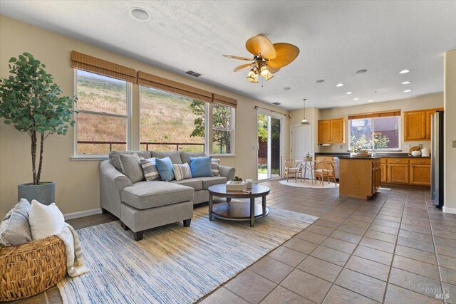 living area with plenty of natural light, a ceiling fan, recessed lighting, baseboards, and tile patterned flooring