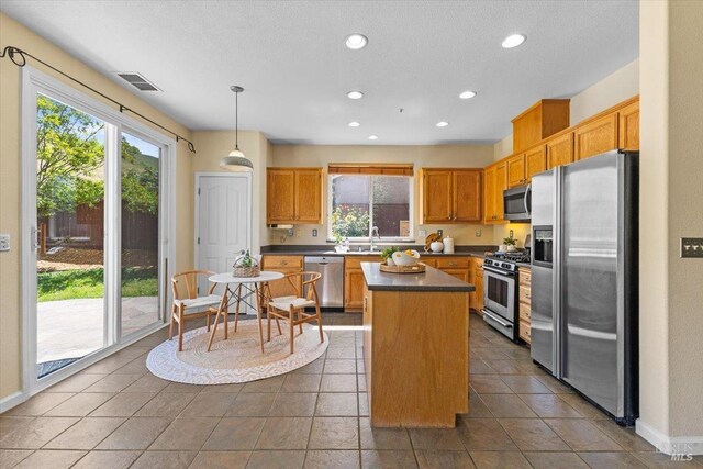 kitchen featuring appliances with stainless steel finishes, dark countertops, a kitchen island, recessed lighting, and baseboards