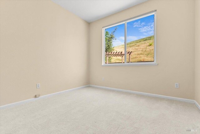 carpeted empty room featuring baseboards