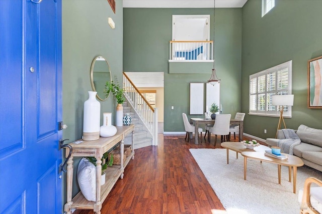 living area featuring a high ceiling, stairs, wood finished floors, and baseboards