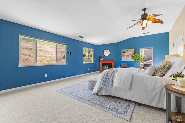 carpeted bedroom with a glass covered fireplace, baseboards, lofted ceiling, and ceiling fan
