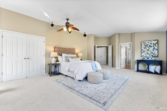 bedroom featuring carpet floors, vaulted ceiling, multiple closets, baseboards, and a ceiling fan