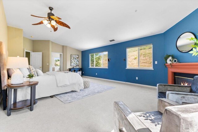 bedroom with carpet flooring, lofted ceiling, a glass covered fireplace, baseboards, and ceiling fan