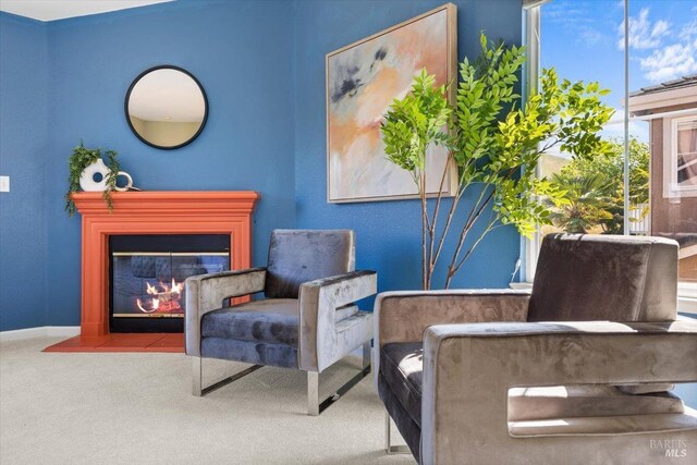 sitting room with a fireplace with flush hearth, carpet floors, and baseboards