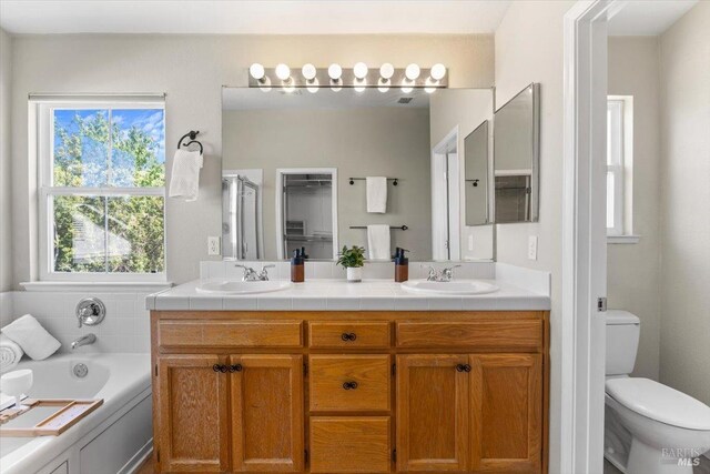 full bath featuring double vanity, a bath, toilet, and a stall shower