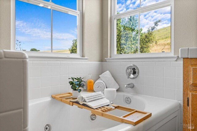 full bath with healthy amount of natural light and a tub with jets