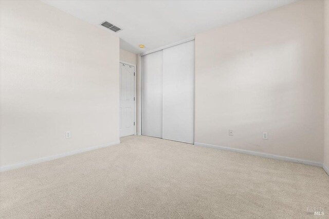 unfurnished bedroom with light colored carpet, baseboards, and a closet