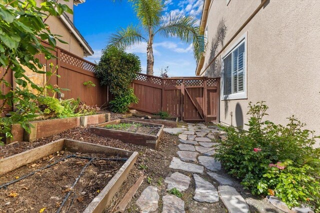 view of yard featuring fence, a garden, and a gate