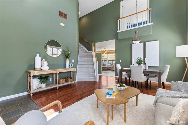 living room with stairway, a towering ceiling, and baseboards