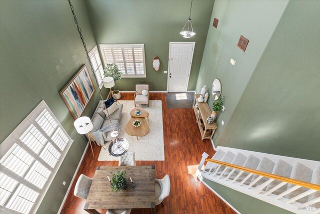 living area featuring a towering ceiling, wood finished floors, and plenty of natural light