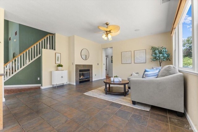 living room with a ceiling fan, stairs, baseboards, and a fireplace