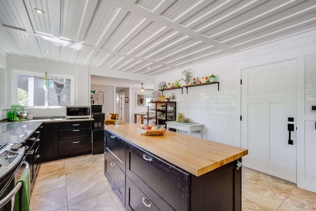 kitchen with wooden counters, a center island, dark brown cabinets, and stainless steel range oven