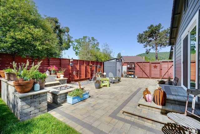 view of patio with a fenced backyard, an outdoor structure, a storage shed, and a gate