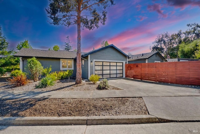 ranch-style house featuring driveway, a garage, and fence