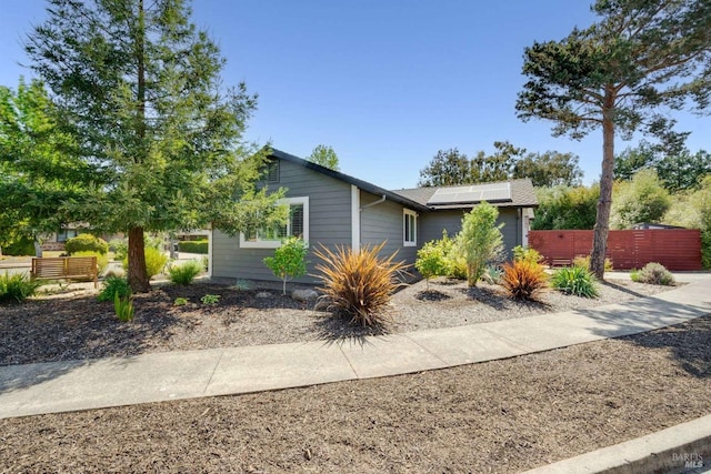 ranch-style house with solar panels and fence