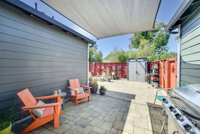 view of patio / terrace featuring a storage shed, an outbuilding, a fenced backyard, and grilling area