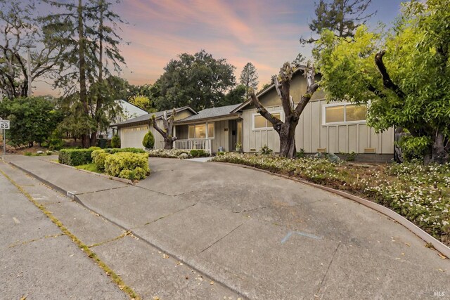 824 W St, Petaluma, CA 94952 - view of front of home with board and batten siding, a porch, a garage, and concrete driveway