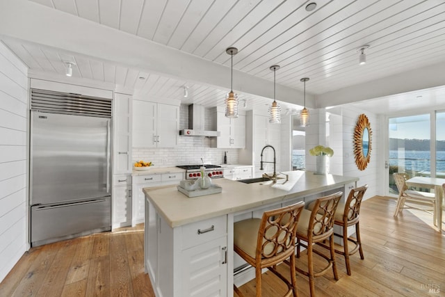 27 W Shore Rd, Belvedere, CA 94920 - kitchen with built in fridge, a sink, wall chimney range hood, white cabinets, and light wood-style floors