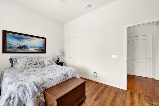 bedroom with baseboards, visible vents, and wood finished floors