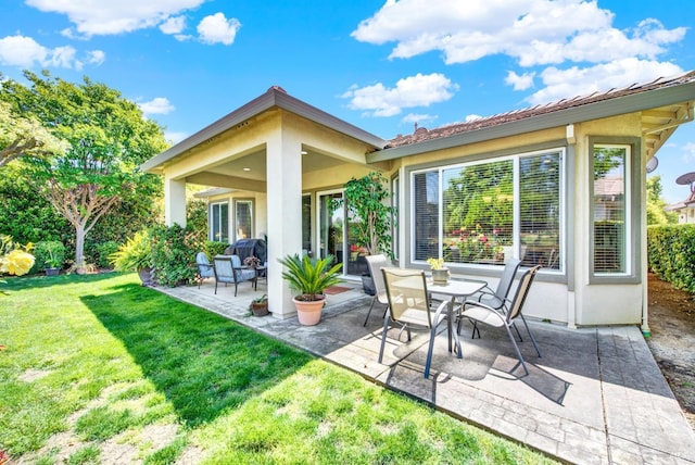 rear view of property with a patio area, stucco siding, and a lawn