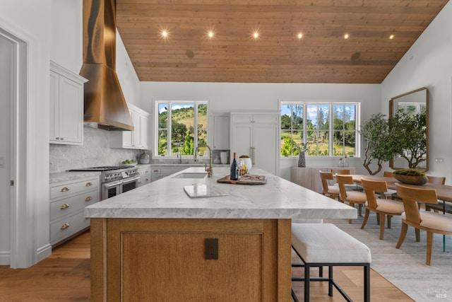 2509 Madrona Ave, Saint Helena, CA 94574 - kitchen with range with two ovens, a sink, high vaulted ceiling, wall chimney range hood, and a center island with sink