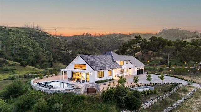 2509 Madrona Ave, Saint Helena, CA 94574 - back of house at dusk with fence, an outdoor pool, metal roof, curved driveway, and a standing seam roof
