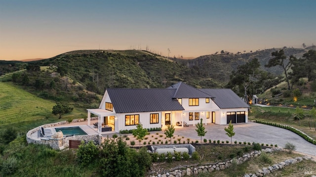 2509 Madrona Ave, Saint Helena, CA 94574 - back of property at dusk featuring a standing seam roof, metal roof, an outdoor pool, a garage, and concrete driveway