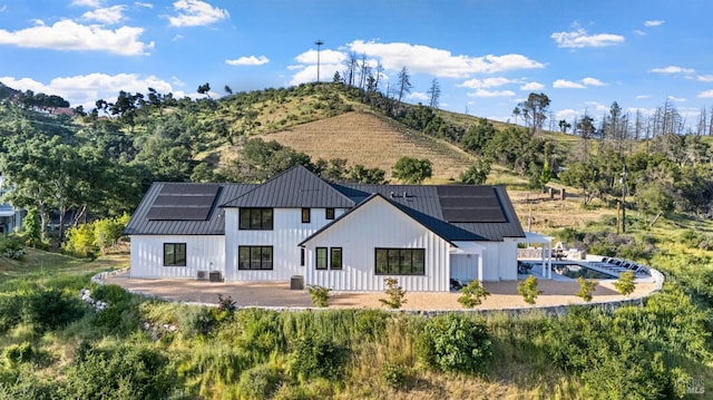 2509 Madrona Ave, Saint Helena, CA 94574 - back of house featuring a patio, board and batten siding, a standing seam roof, and roof mounted solar panels