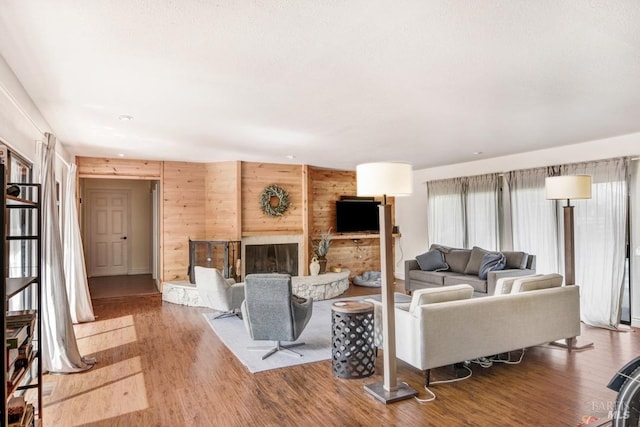 living area with wood walls, a fireplace with raised hearth, and wood finished floors