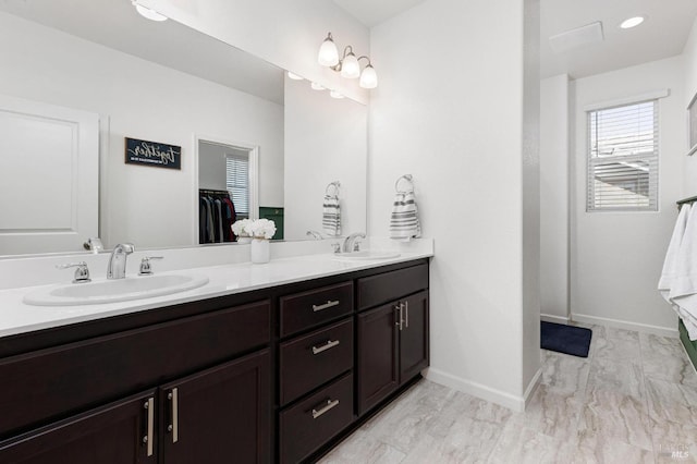 bathroom with baseboards, marble finish floor, double vanity, and a sink