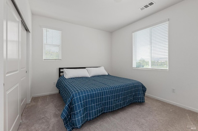bedroom featuring carpet, a closet, visible vents, and multiple windows